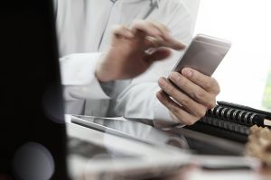 Businessman hand using laptop and mobile phone on wooden desk as concept